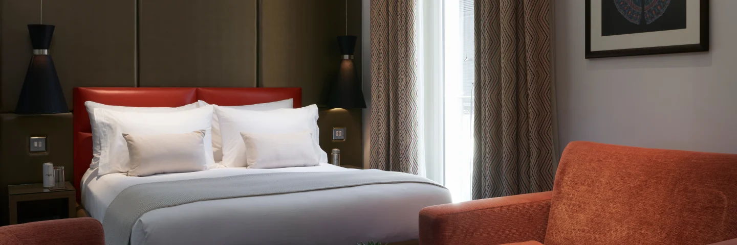 Premium King Deluxe room with a king bed, red cushion and orange armchairs