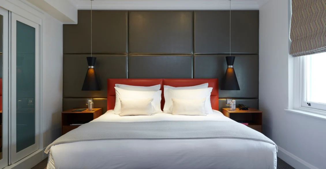 Junior Suite bedroom with a king bed, padded headboard and pendant lights