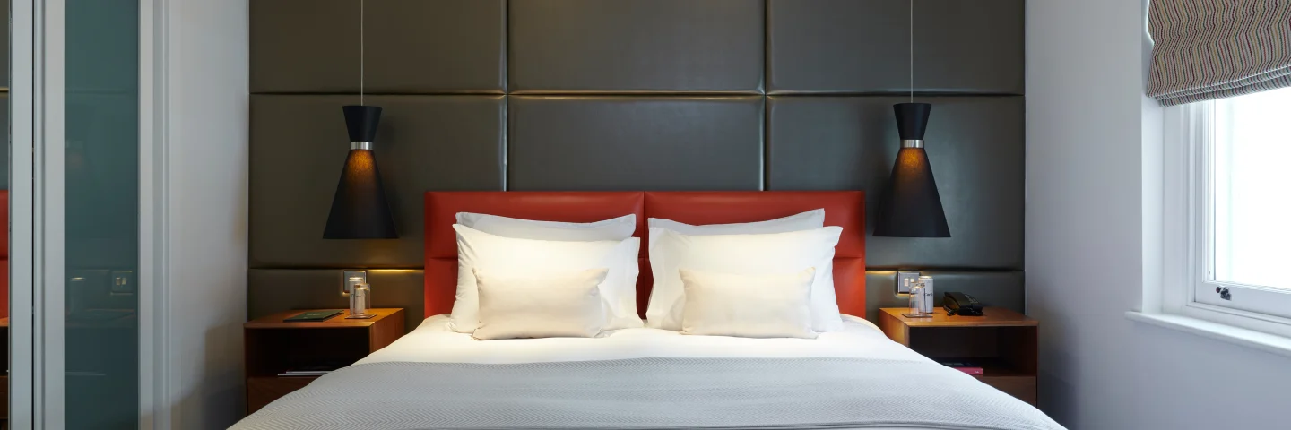 Junior Suite bedroom with a king bed, padded headboard and pendant lights