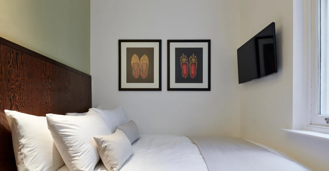 Standard Double room with a double bed, two framed prints and wall-mounted TV