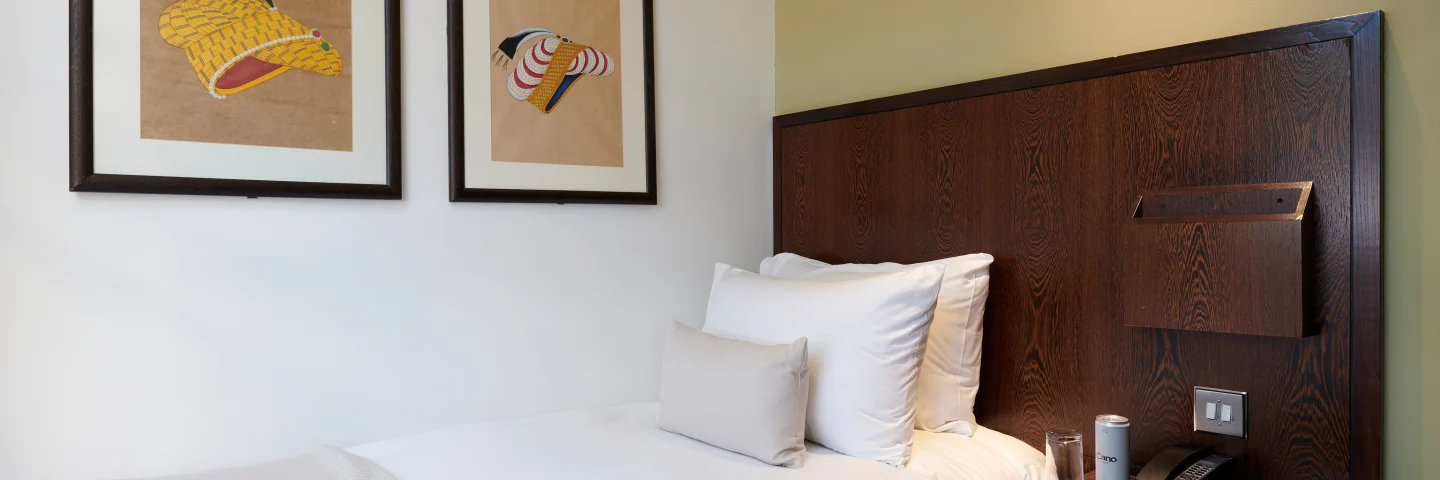Standard Single room with a single bed, dark wood headboard and two framed prints