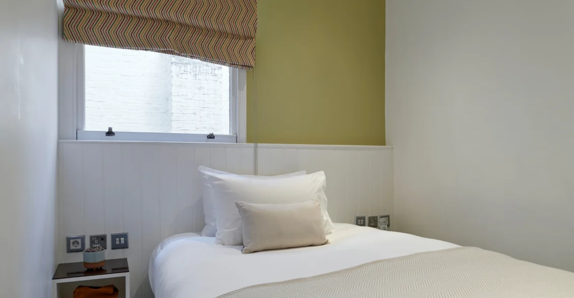 Superior Single room with a double bed, green accent wall and roman blind