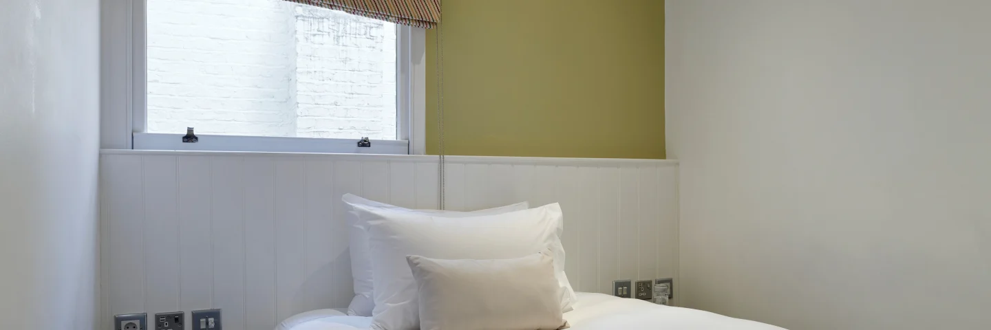 Superior Single room with a double bed, green accent wall and roman blind