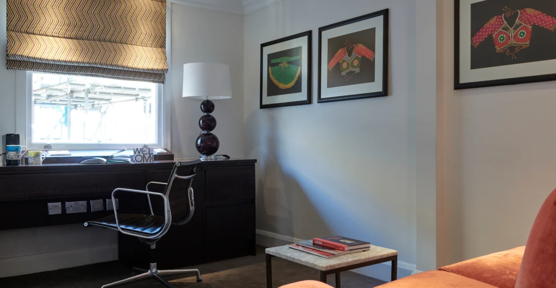 Junior Suite living area with an orange sofa, desk and framed prints