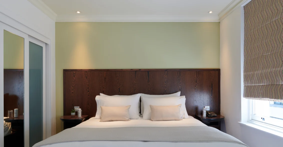 Premium King room with a king bed, dark wood headboard and green accent wall