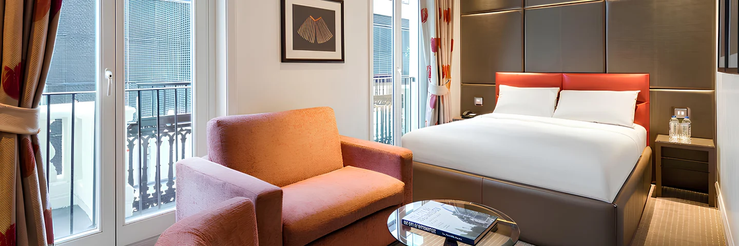Premium King Deluxe room with orange armchairs, glass table and a king bed by French windows