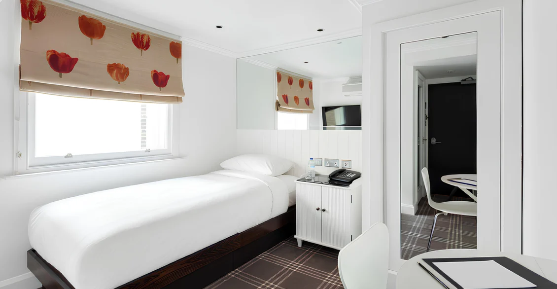 Single room with a single bed, poppy-print blinds and desk