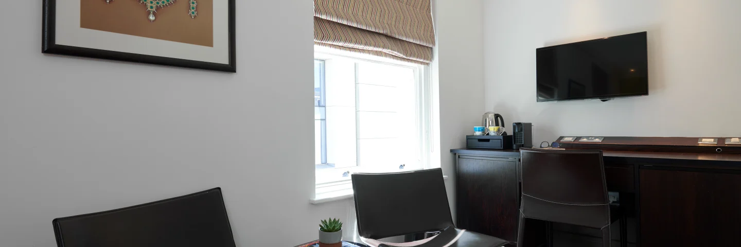 Sitting area in a Premium King room with leather chairs, desk and TV