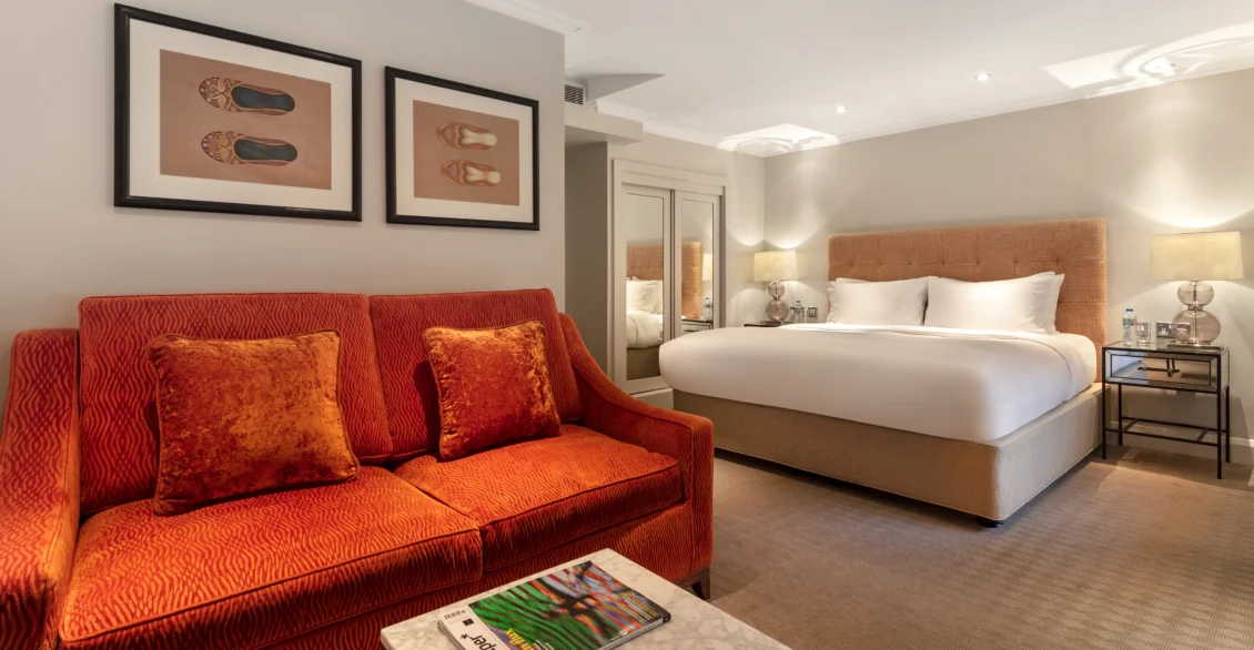 Junior Suite with an orange sofa, bed and framed prints