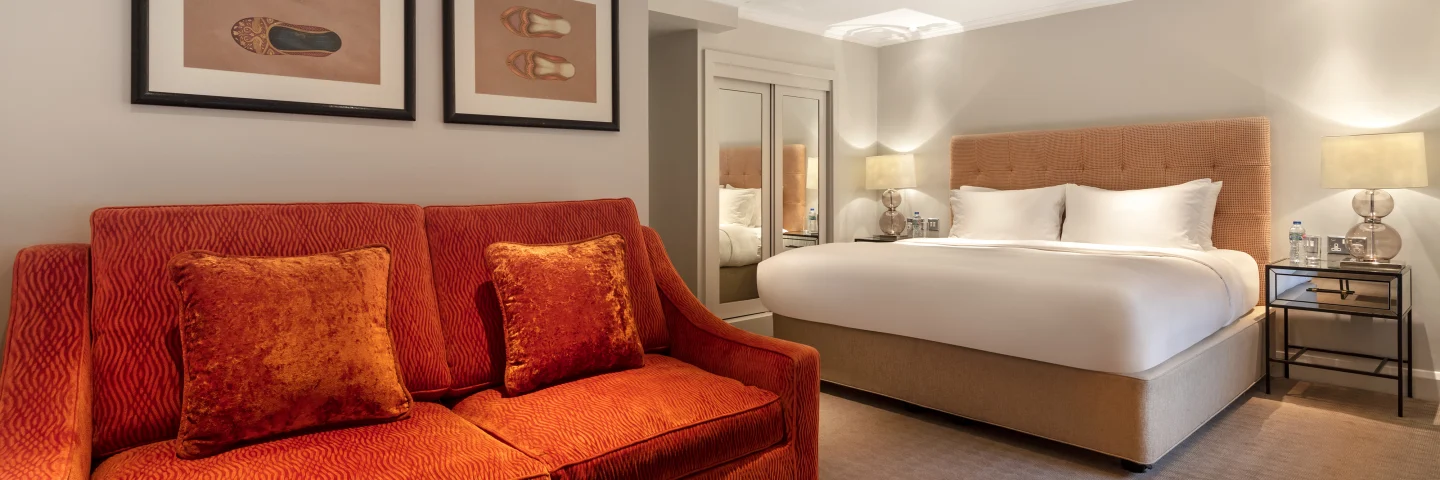 Junior Suite with an orange sofa, bed and framed prints