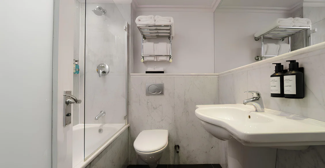 Marble bathroom with bath, shower screen and basin