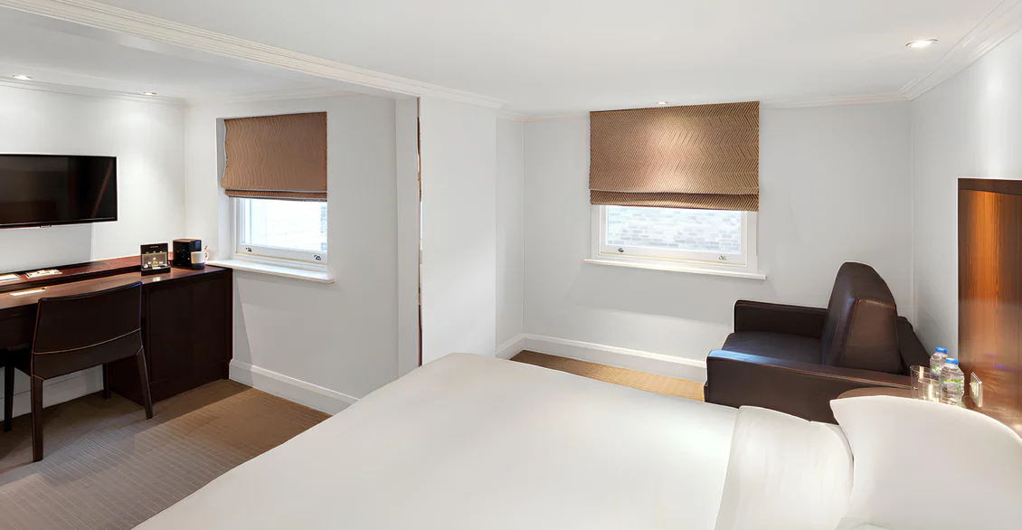 Premium King Deluxe room with a king bed, desk, armchair and three windows