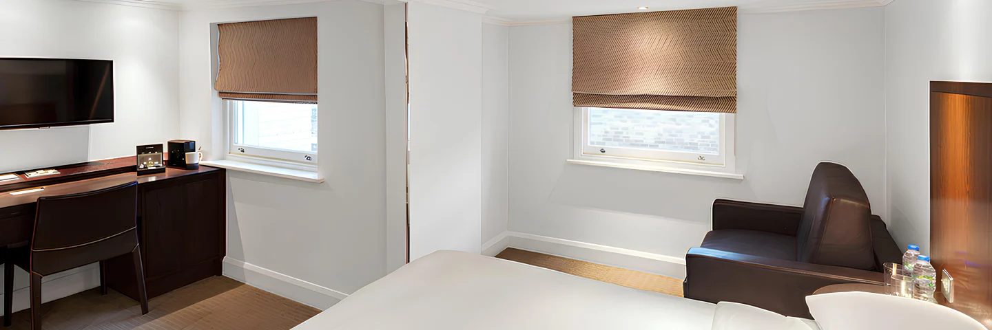 Premium King Deluxe room with a king bed, desk, armchair and three windows