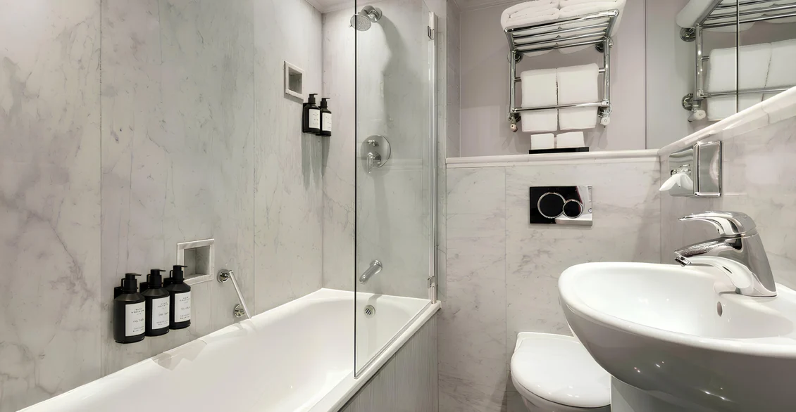 Marble bathroom with bath, shower screen and towel rail