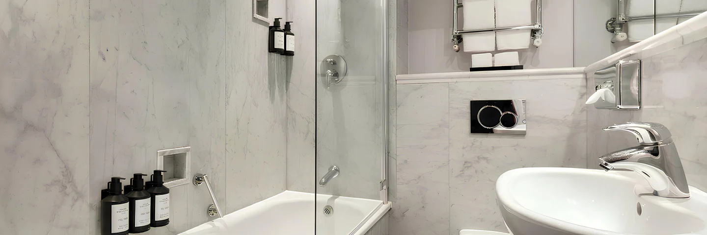 Marble bathroom with bath, shower screen and heated towel rail