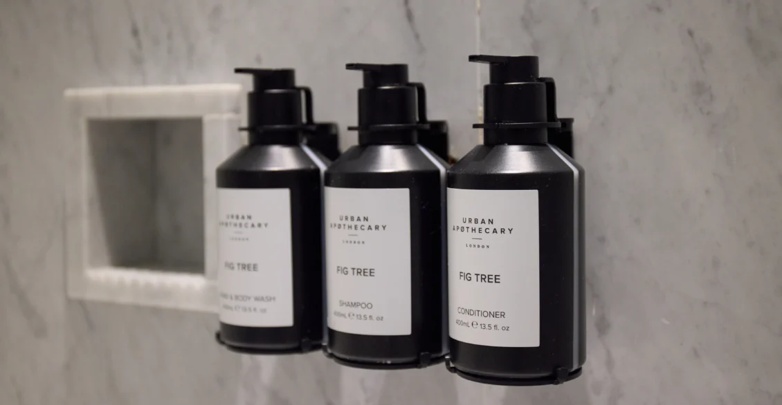 Three black toiletry bottles in a marble bathroom niche