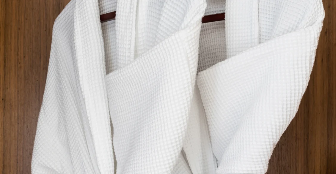Two white bathrobes hanging in a wardrobe