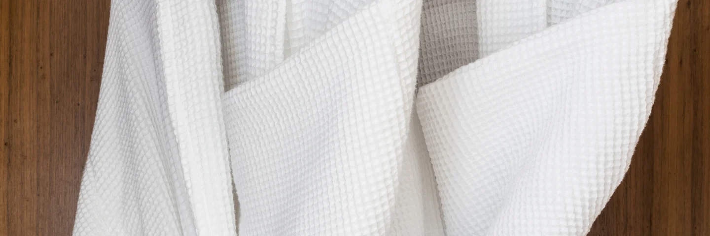 Two white bathrobes hanging in a wardrobe