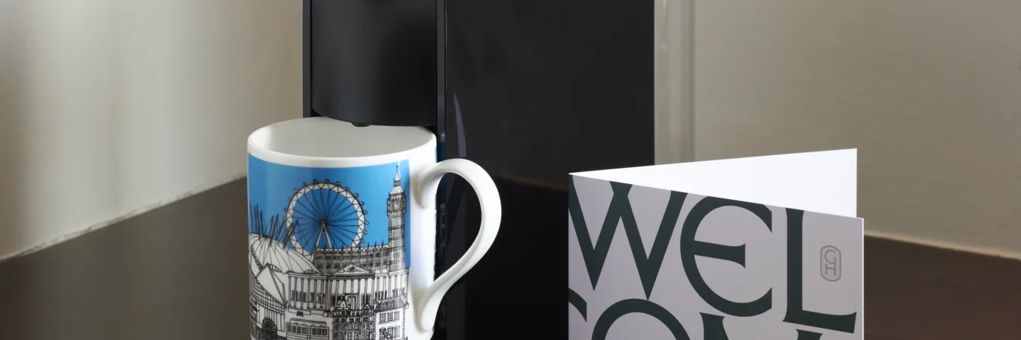 Guild Hotels London mug and a welcome card on a dark table