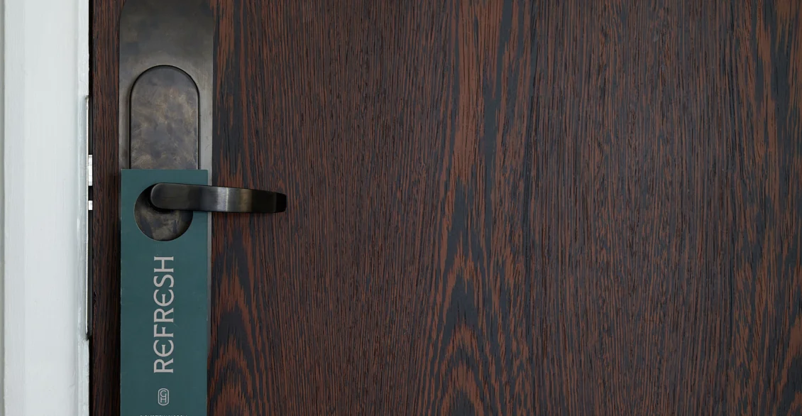 Dark wood hotel room door with a 'Refresh' door hanger