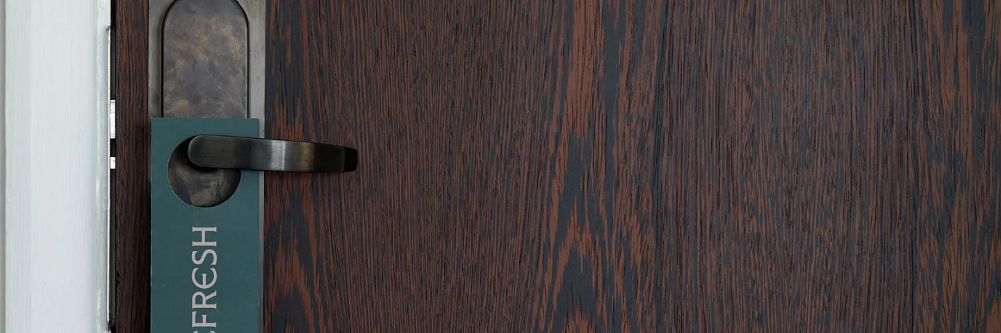 Dark wood hotel room door with a 'Refresh' door hanger