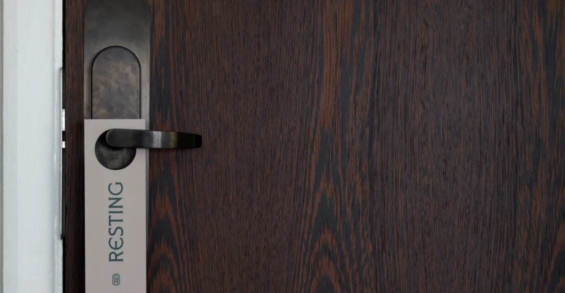 Dark wood hotel room door with a 'Resting' door hanger
