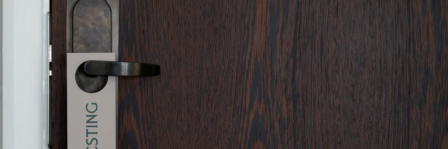 Dark wood hotel room door with a 'Resting' door hanger