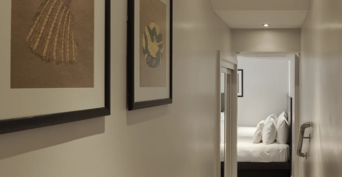 Hallway into a Standard Twin room with framed prints and a bed beyond