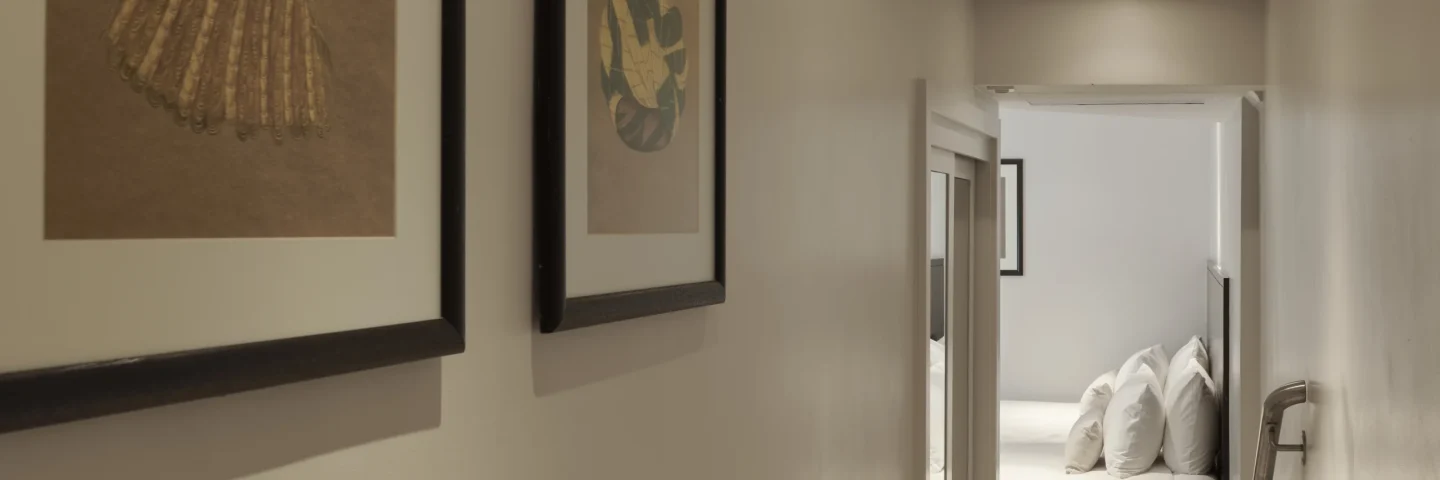 Hallway into a Standard Twin room with framed prints and a bed beyond