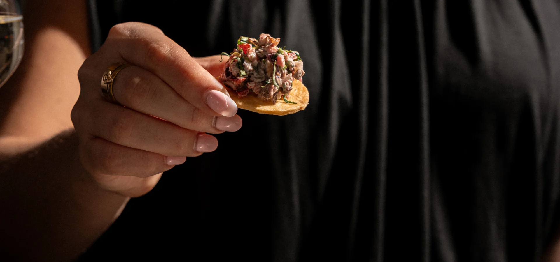 Guest lifting a steak tartare canapé from a slate serving plate