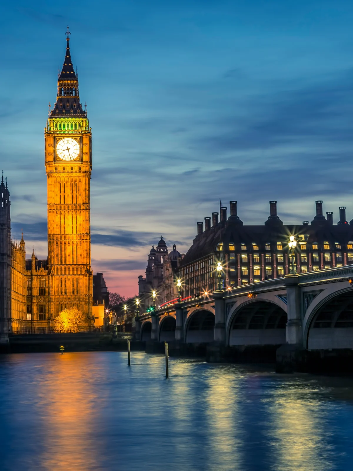 Big Ben and the Houses of Parliament lit at dusk, seen across the Thames