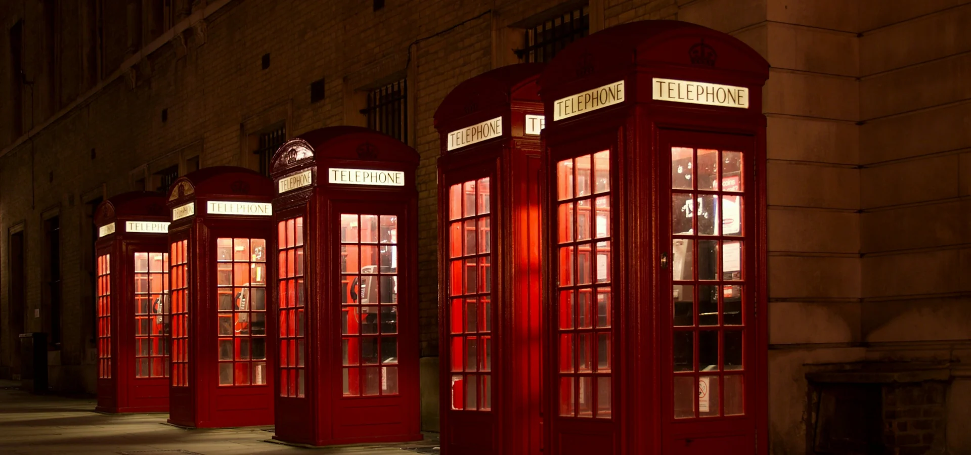 Row of red telephone boxes lit at night