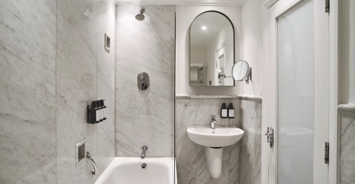 City Single bathroom with shower over bath, sink and arched mirror