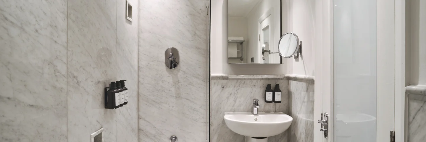 City Single bathroom with shower over bath, sink and arched mirror