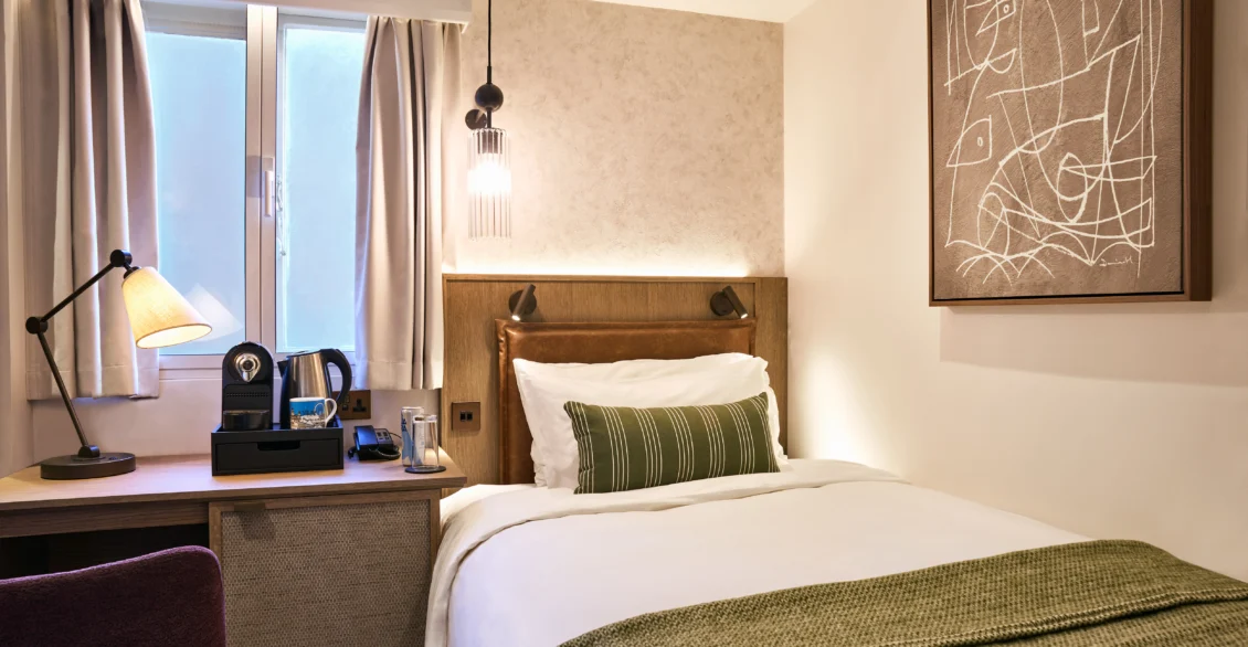 City Single room with single bed, green throw and desk beneath a window
