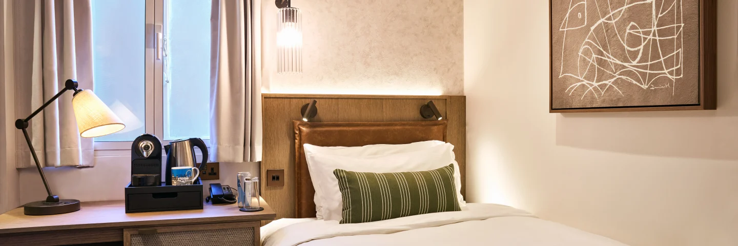 City Single room with single bed, green throw and desk beneath a window