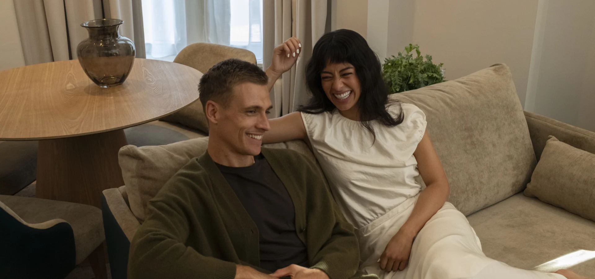 Couple laughing together on a sofa in a suite at Guild Hotel Fitzrovia