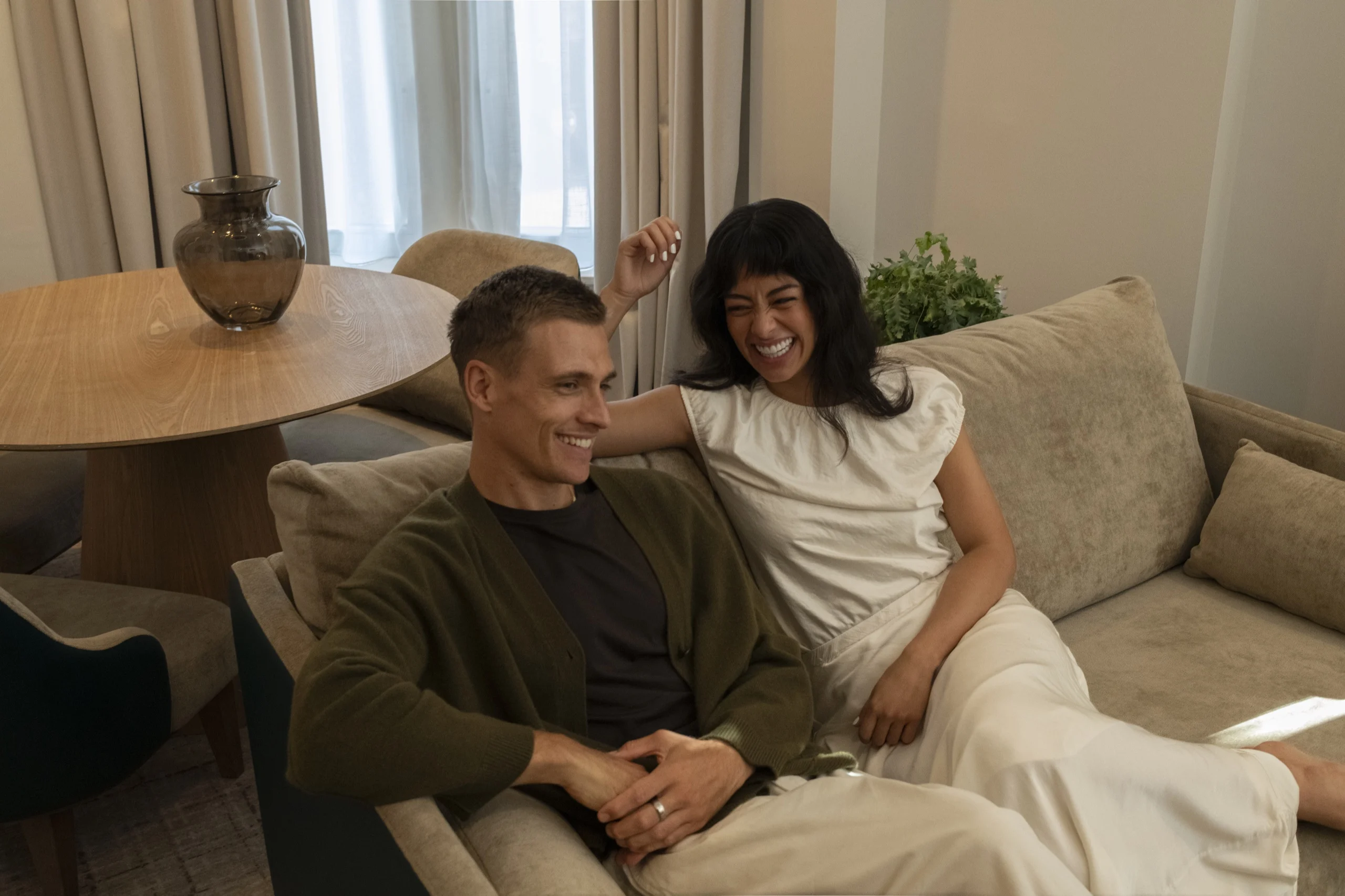 Couple laughing together on a sofa in a suite at Guild Hotel Fitzrovia