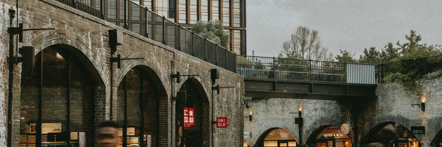 Cyclists passing the brick arches and shops of Coal Drops Yard