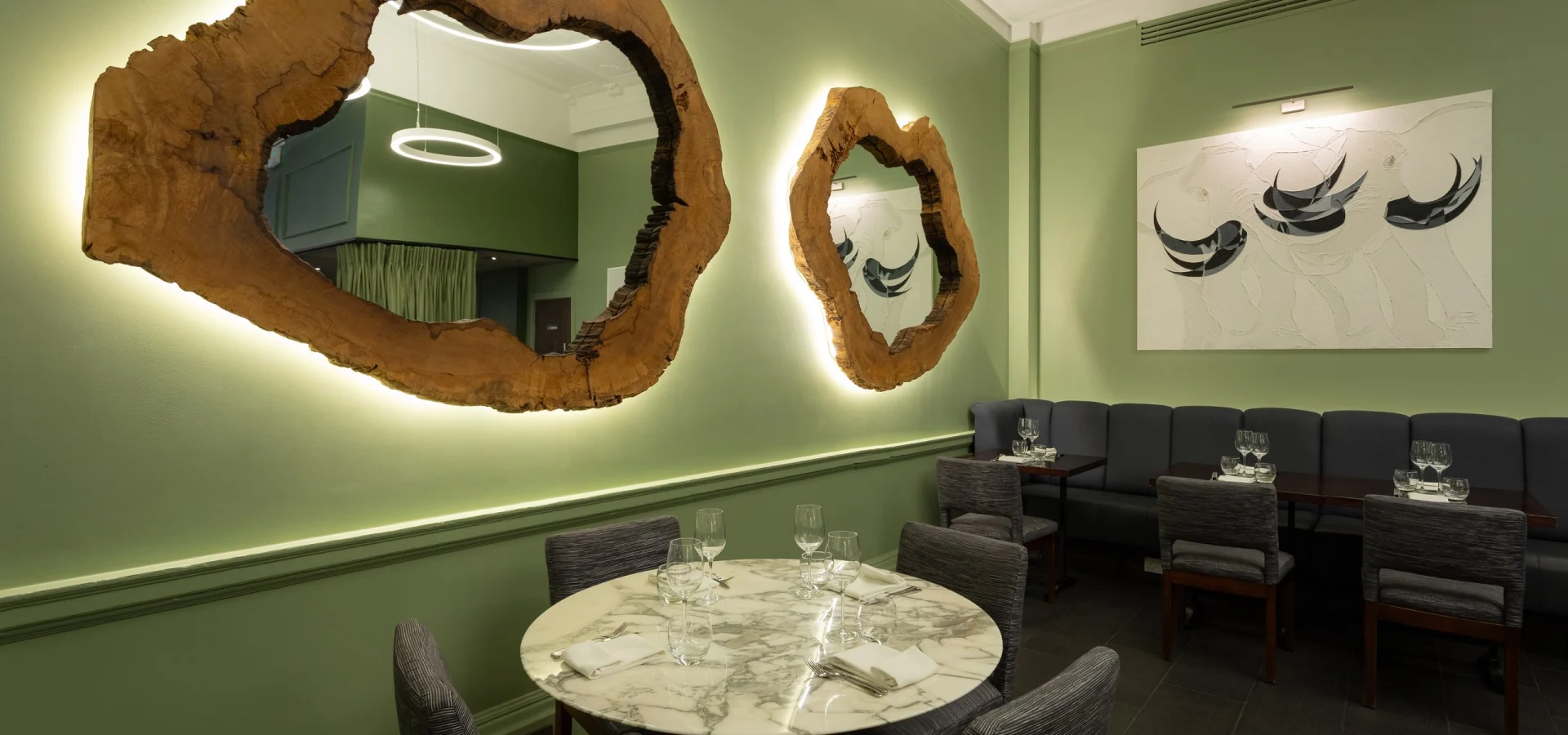 Green dining room with sculptural wood mirrors and marble tables at Steak & Lobster Fitzrovia