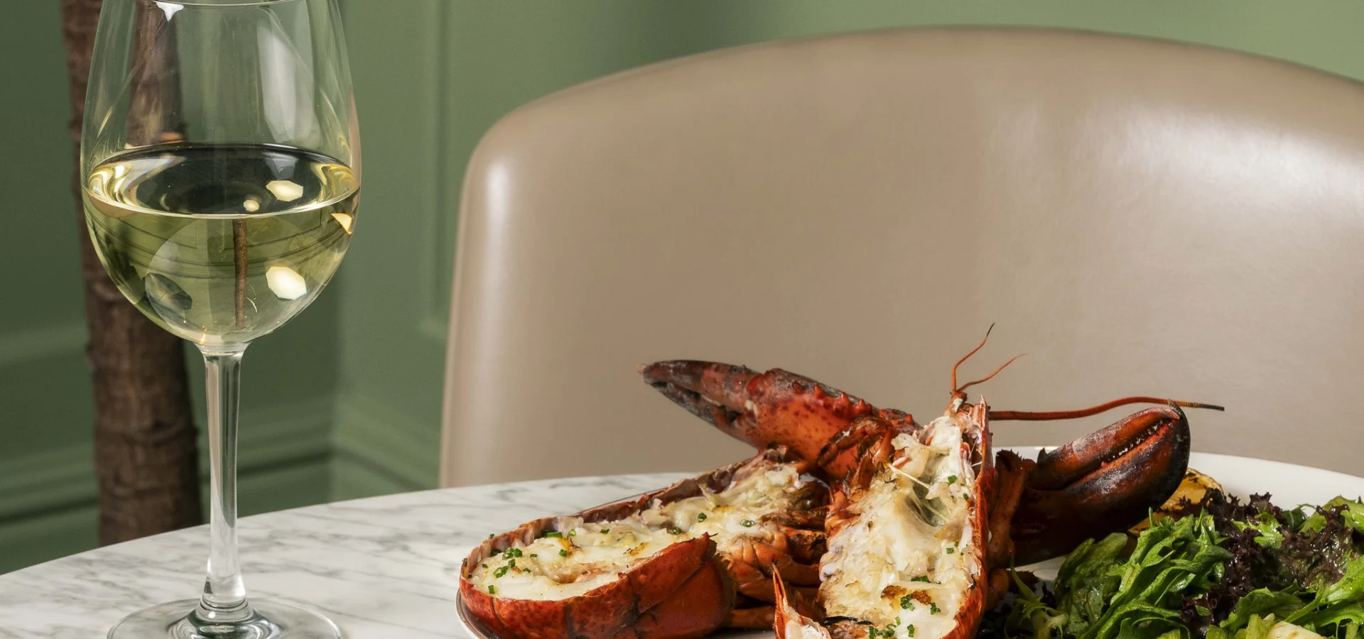 Lobster, fries, salad and white wine on a marble table at Steak & Lobster Fitzrovia
