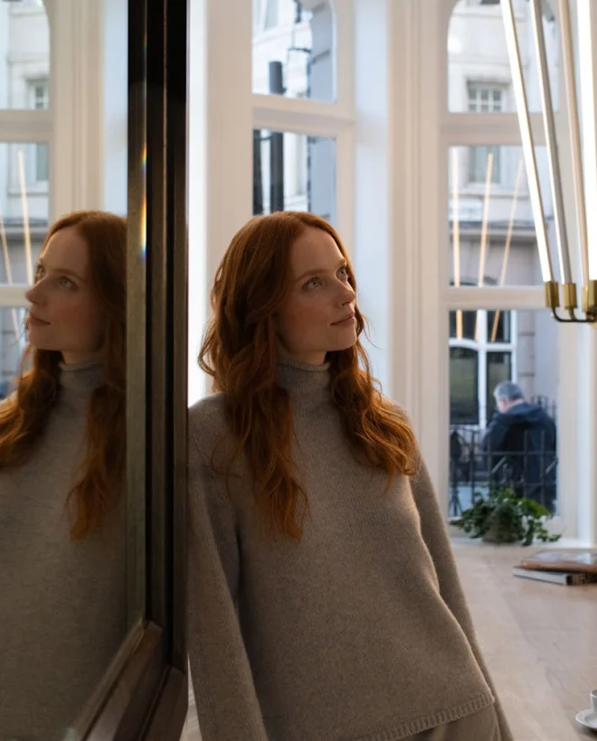 Guest leaning against a mirrored pillar beside the bay window of the Bloomsbury Street Lounge, brass pendant lights above