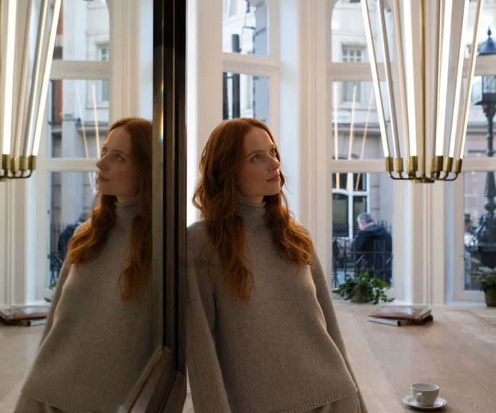 Guest leaning against a mirrored pillar beside the bay window of the Bloomsbury Street Lounge, brass pendant lights above